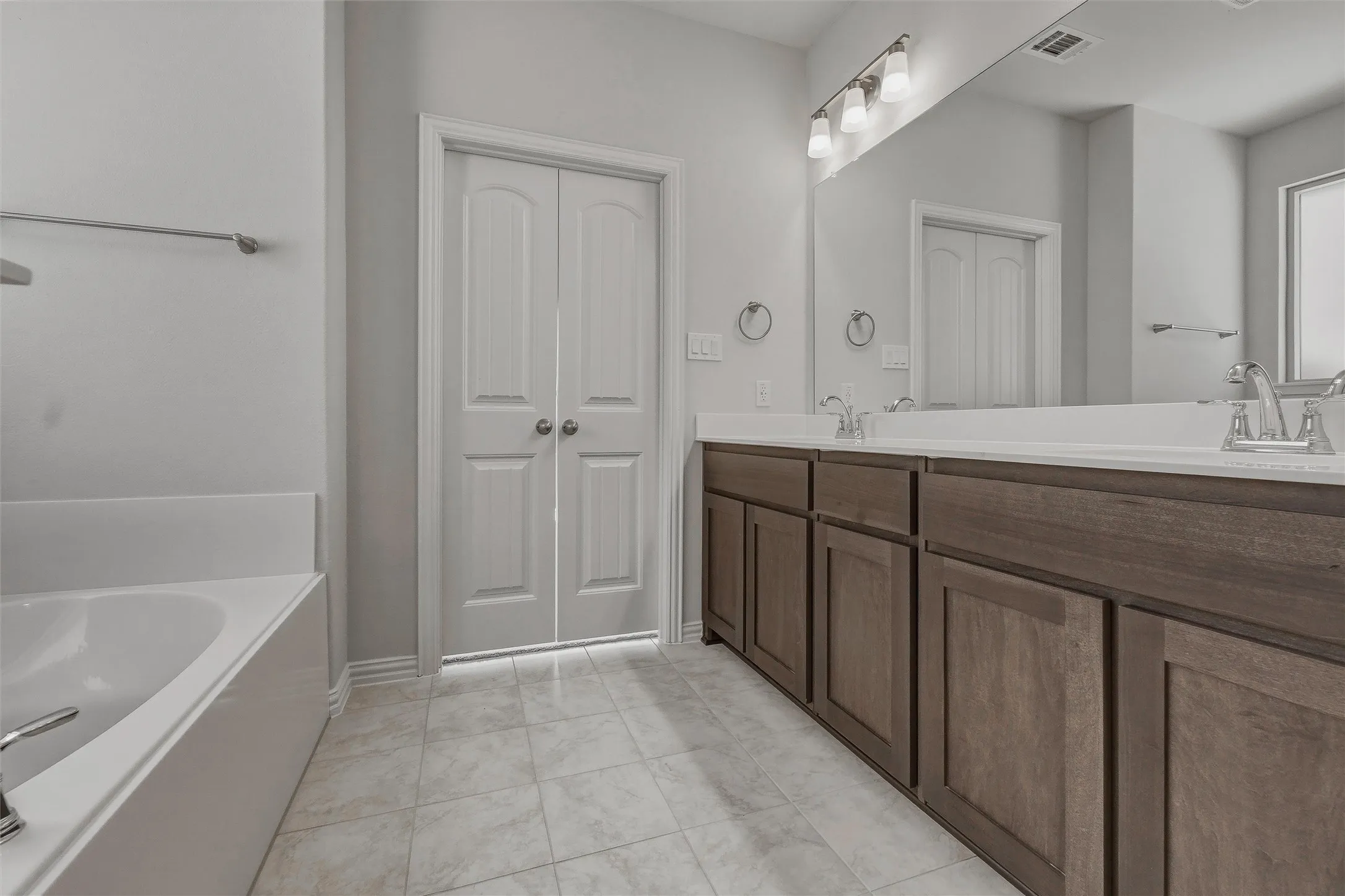Dual sink vanity with dark wood-finish cabinetry, white countertops, and full-width mirror