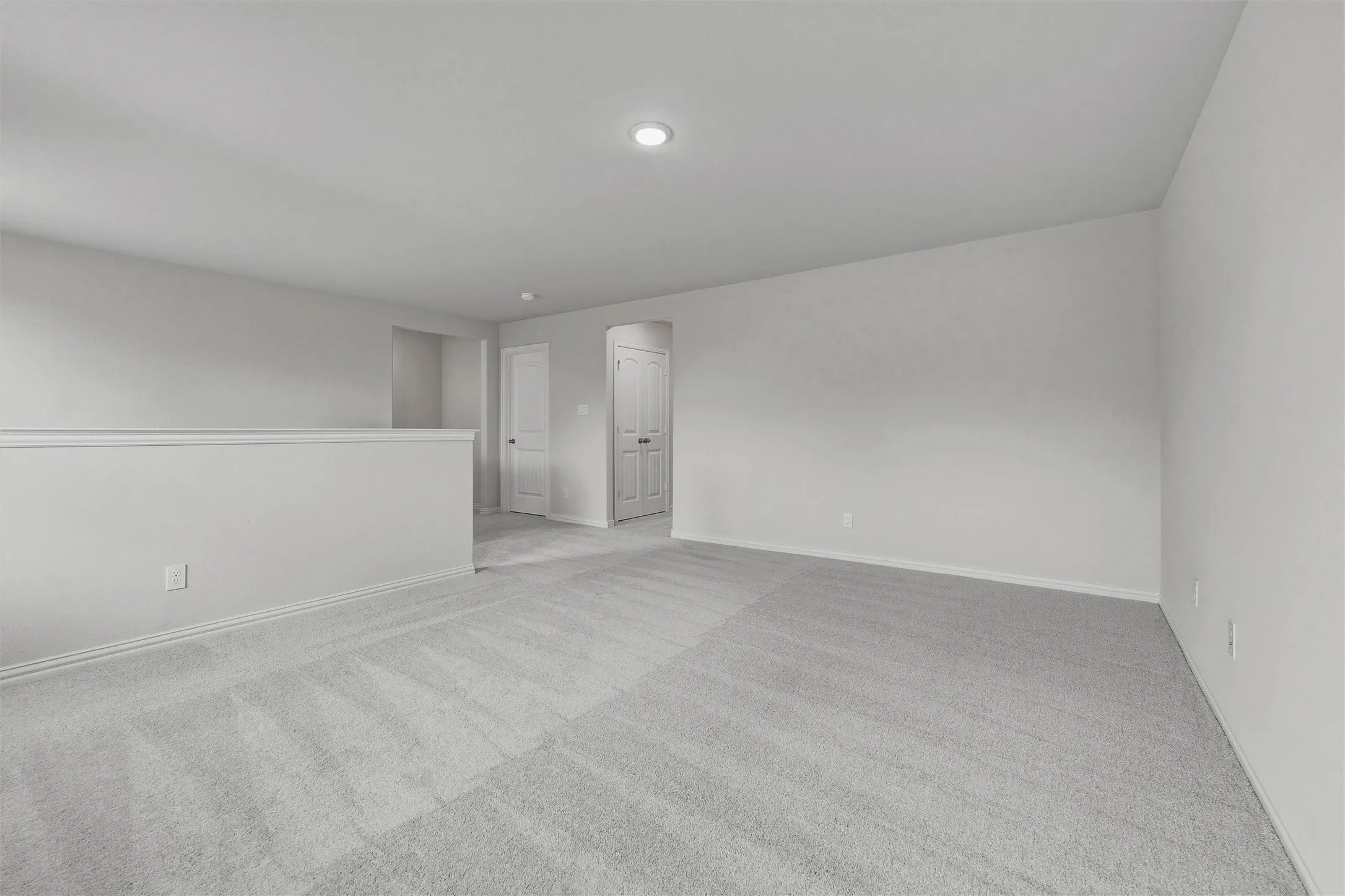 Recessed ceiling lighting, light gray wall finishes, light gray carpeting, half-wall partition, and white trim molding