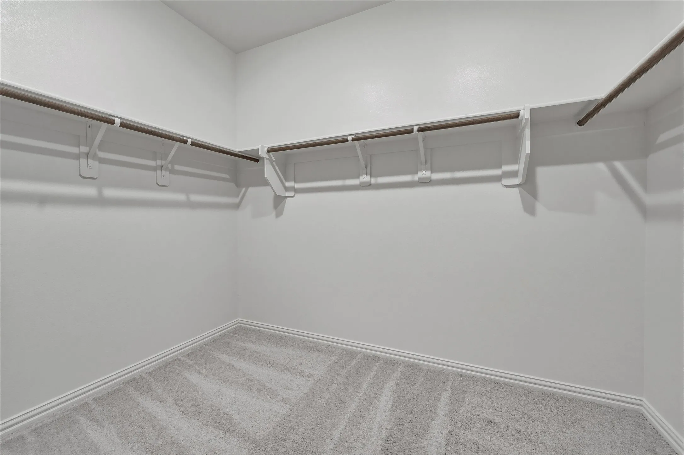 Wall-to-wall carpeting with light-toned walls and wood-finish closet rods