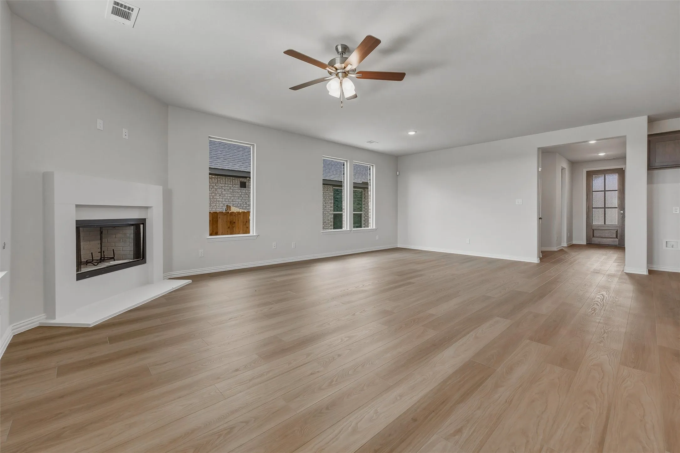 Spacious living area featuring wood-finish flooring, a contemporary fireplace, and multiple windows for abundant natural light