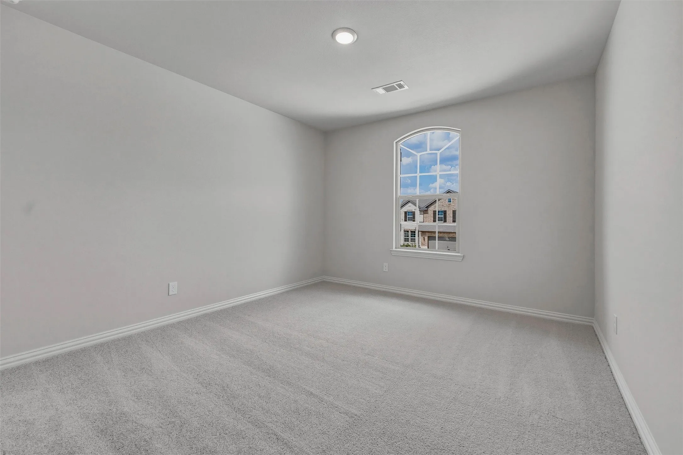 Arched window with gridded panes, recessed ceiling lighting, and light gray wall paint
