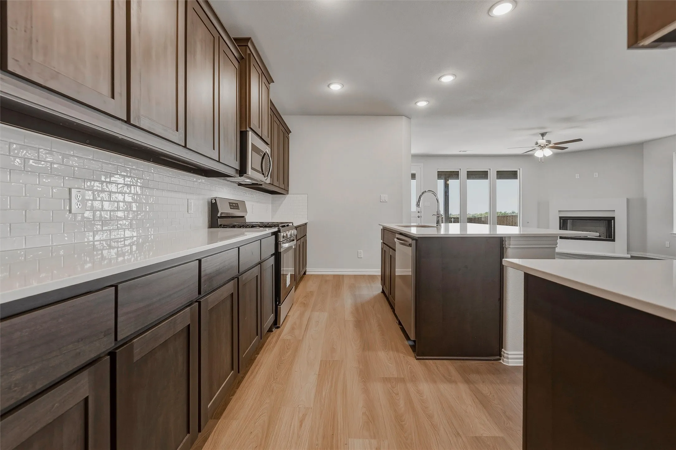 Gourmet kitchen featuring dark wood-finish cabinetry, light countertops, subway tile backsplash, and stainless steel appliances