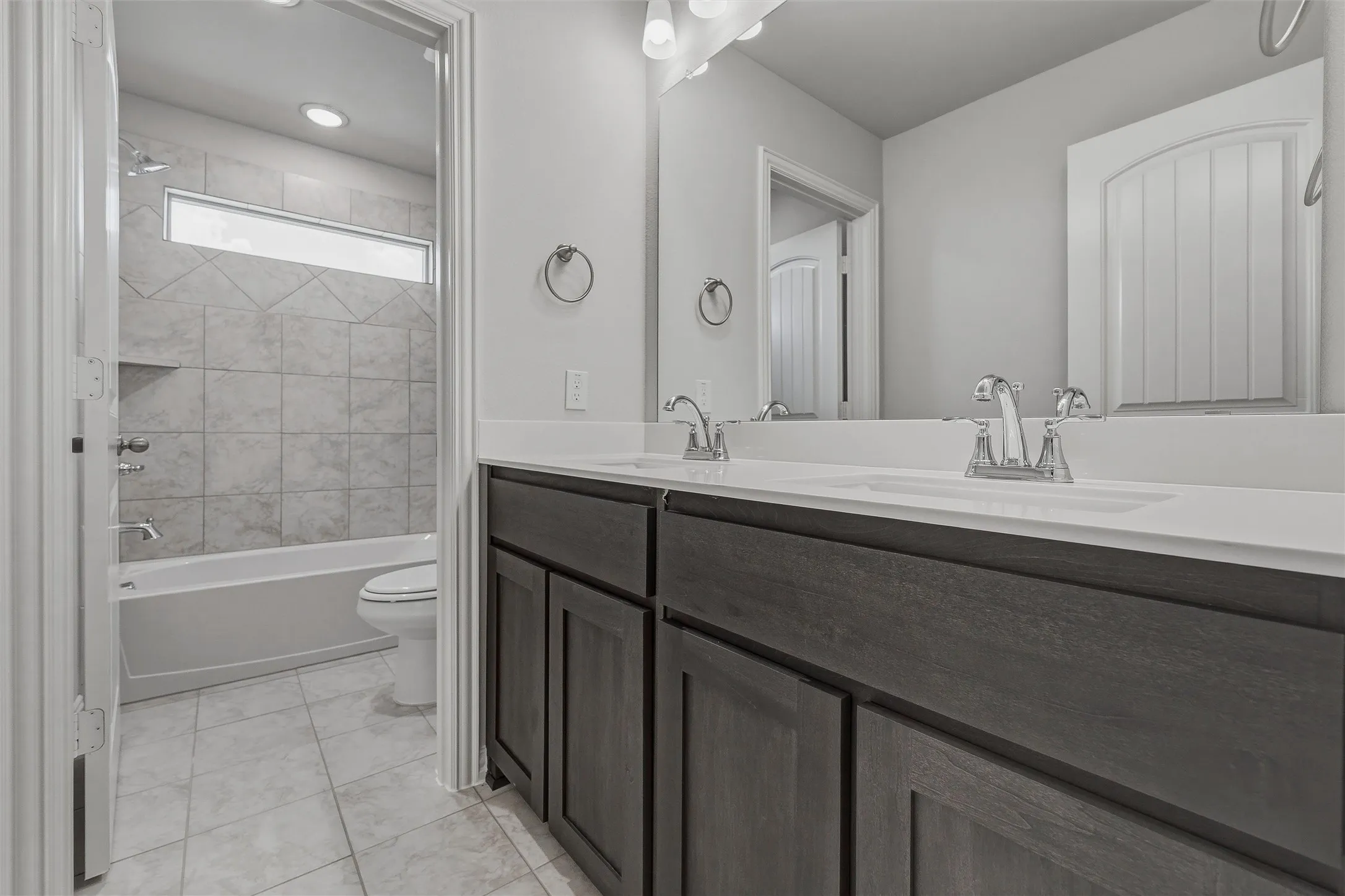 Dual sink vanity with dark wood-finish cabinetry and white countertops