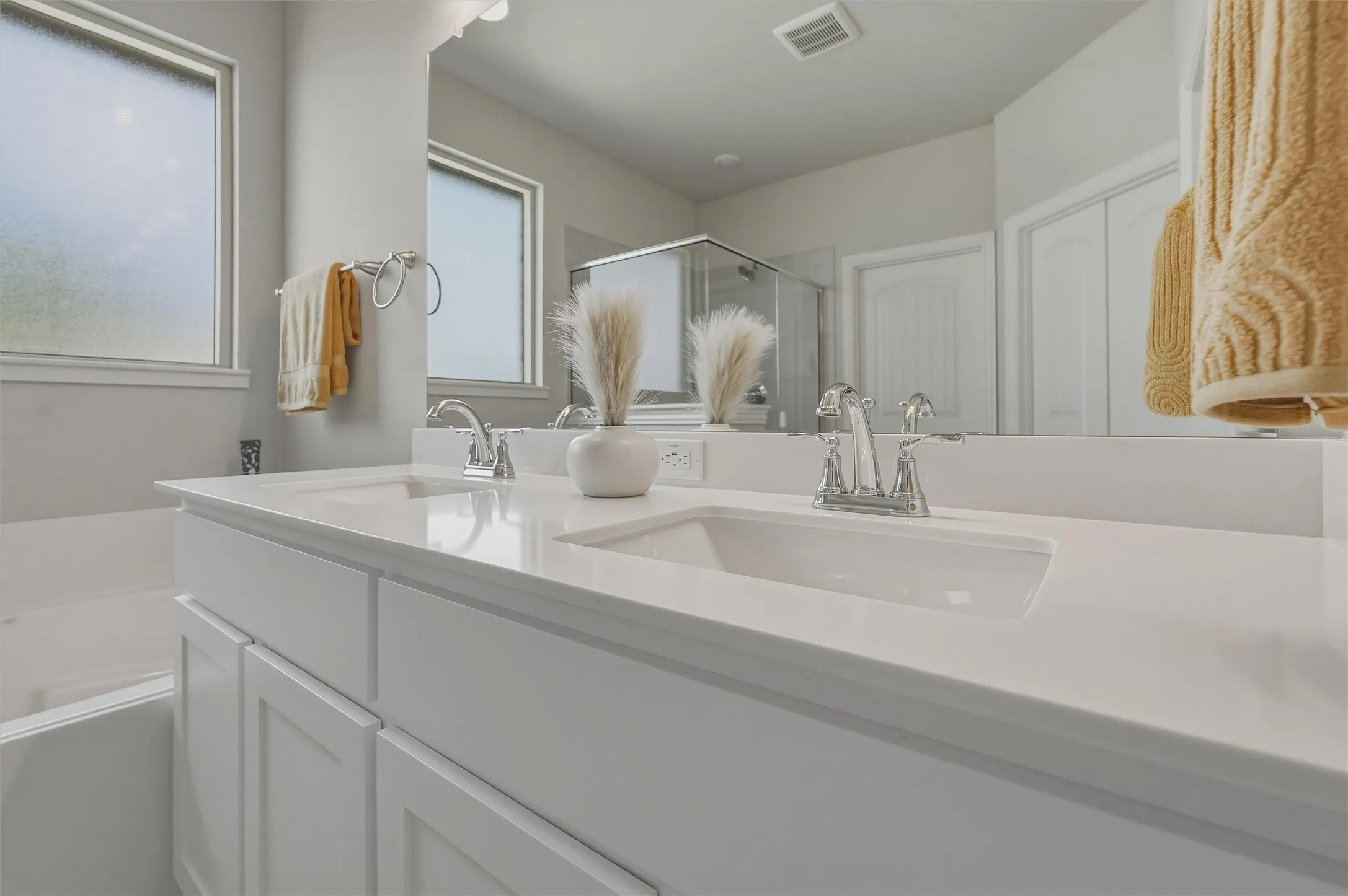 Double vanity with white cabinetry, integrated sinks, chrome fixtures, and a large wall-mounted mirror
