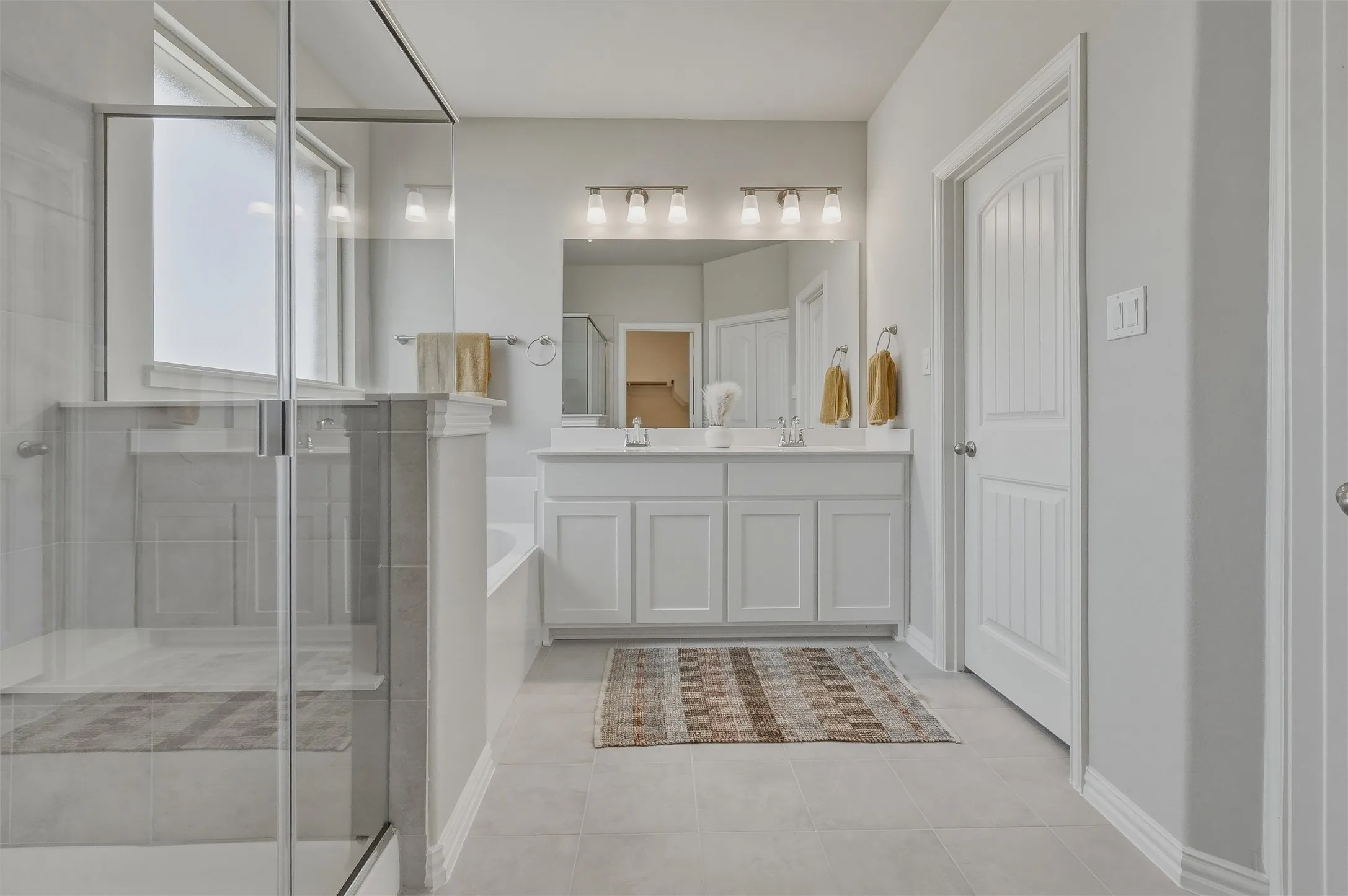 Glass-enclosed shower with a built-in bench, dual vanity with undermount sinks, and a separate soaking tub