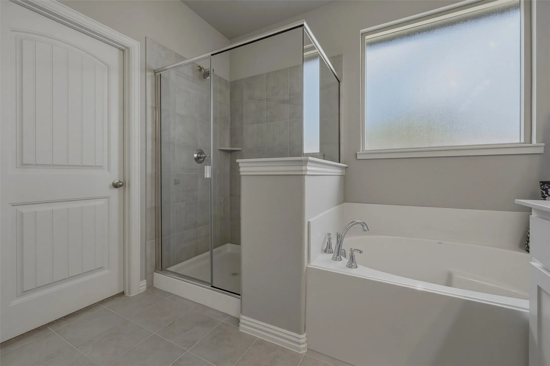 Integrated shower and soaking tub, tiled flooring, frosted window, and beadboard panel door