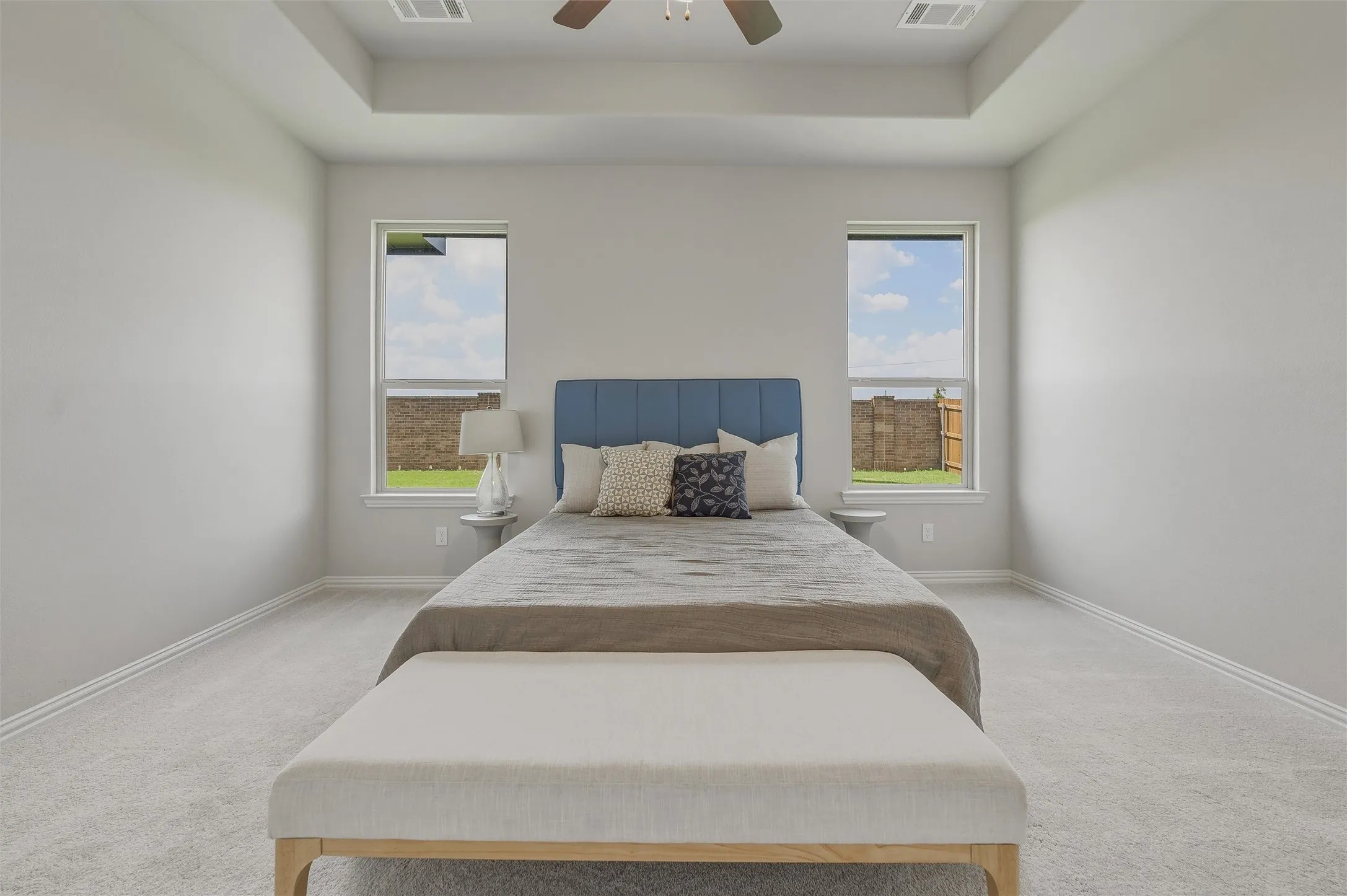 Tray ceiling with recessed lighting, carpeted flooring, two large windows, and a ceiling fan