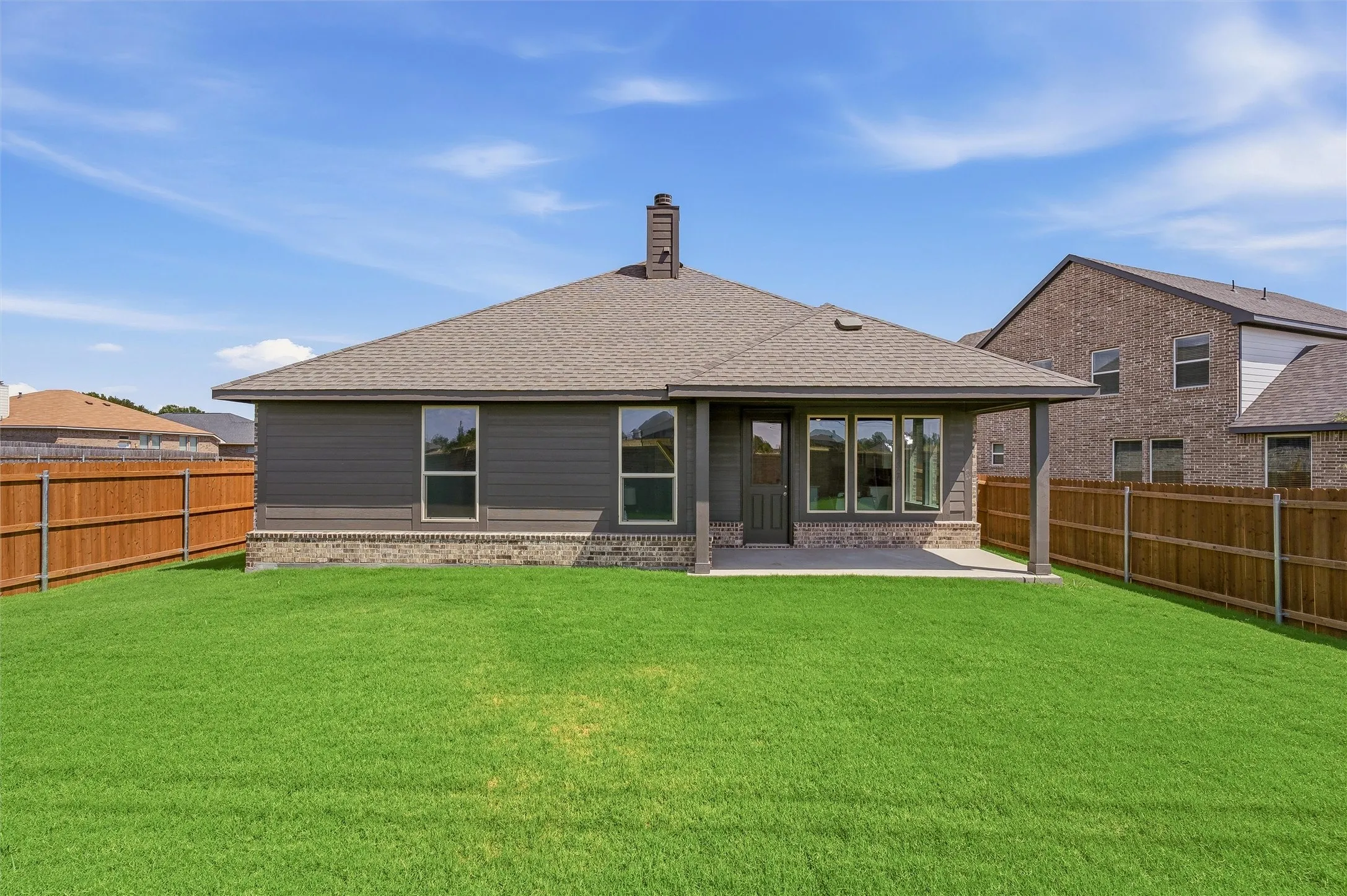 Expansive backyard with a covered patio, wood fencing, and a shingled roof