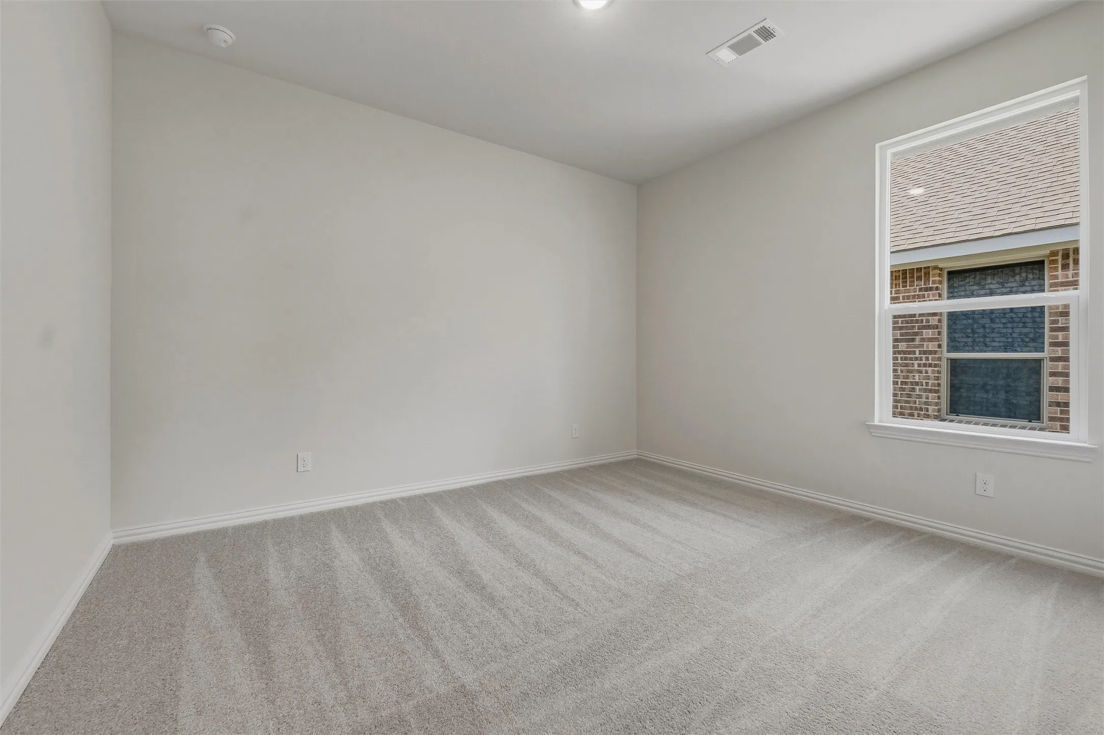 Neutral wall finishes with a large window, recessed lighting, and grey patterned carpeting