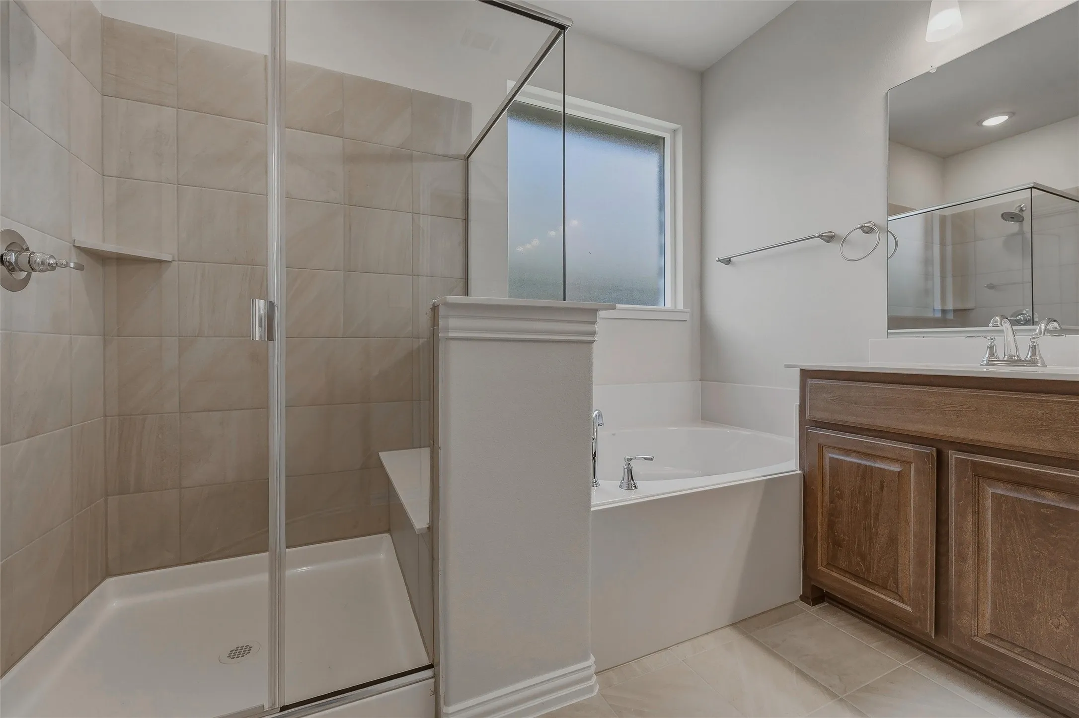 Glass-enclosed shower with tiled walls and an integrated bench