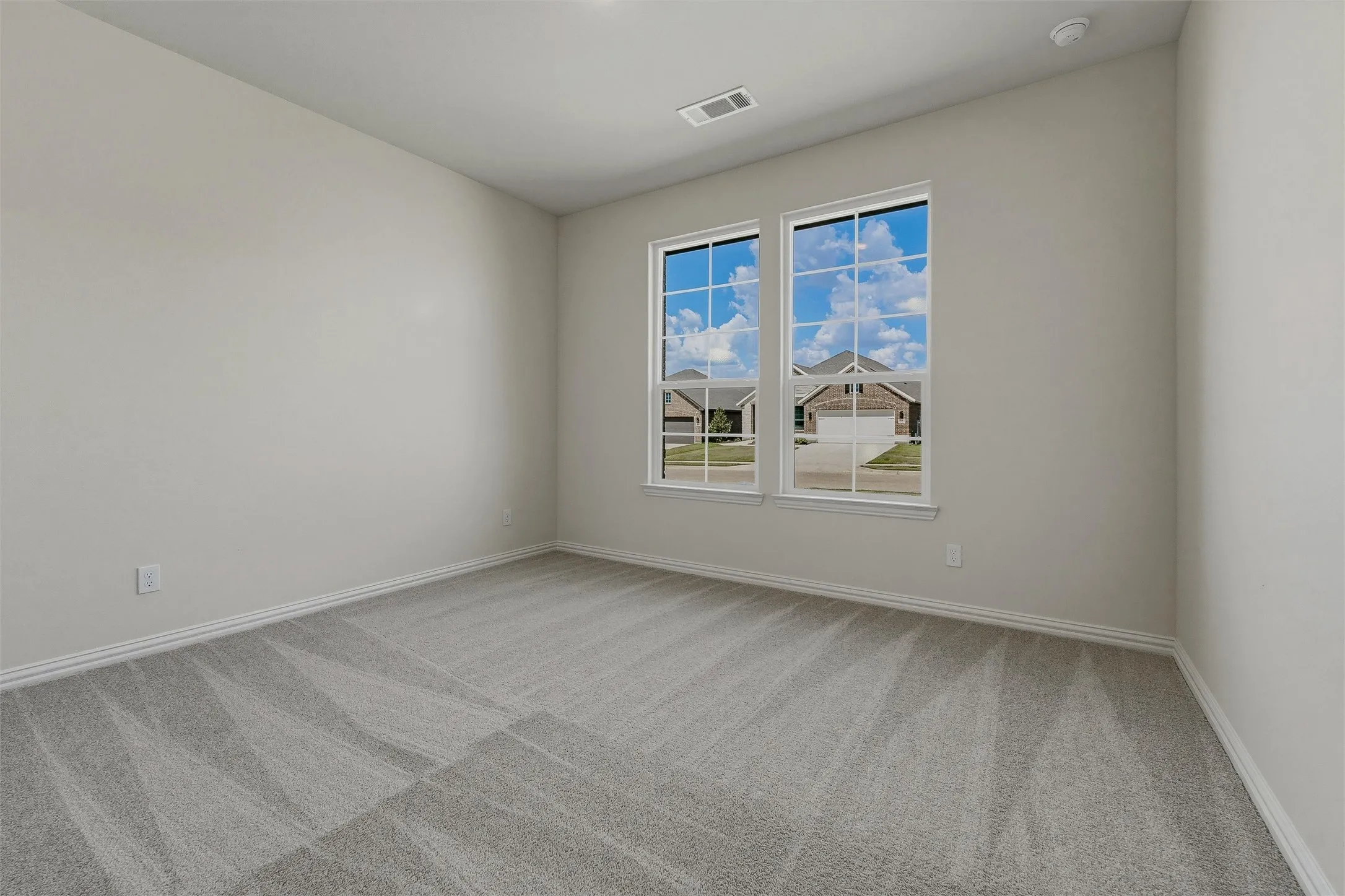 Two large windows with white trim, light gray carpet, and white wall paint