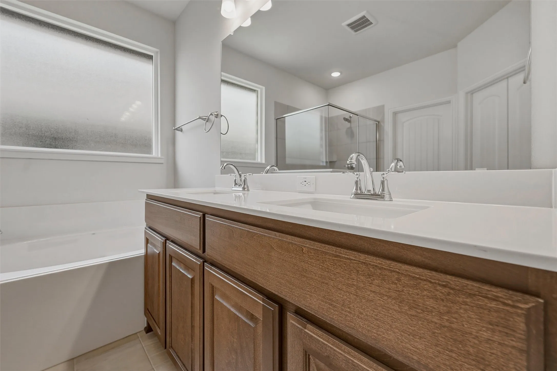 Dual vanity with white undermount sinks, wood-finish cabinetry, and white countertops