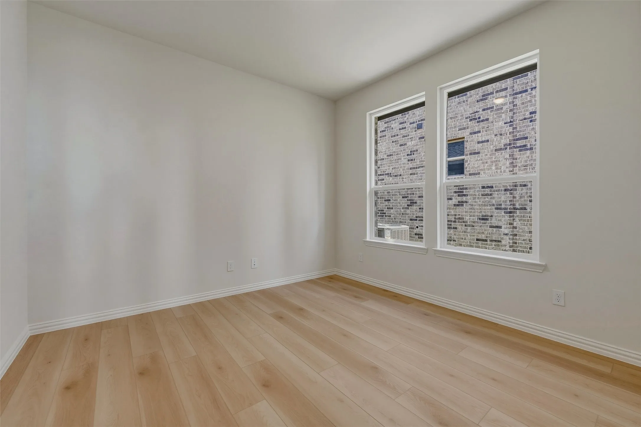 Light wood-finish flooring, white walls, and two large windows with white trim