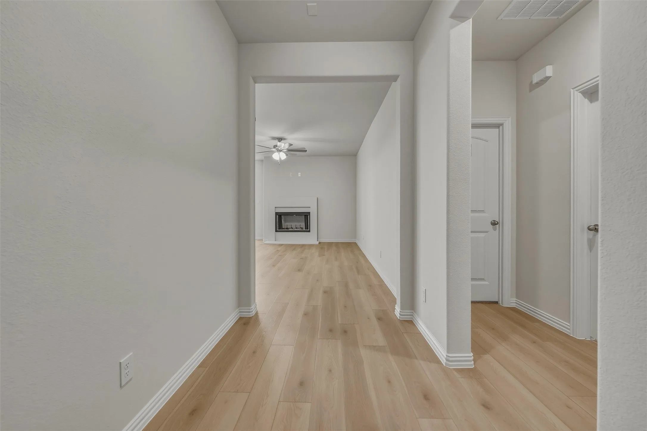 Wood-finish flooring throughout, white walls, white trim, and a built-in fireplace with a mantel