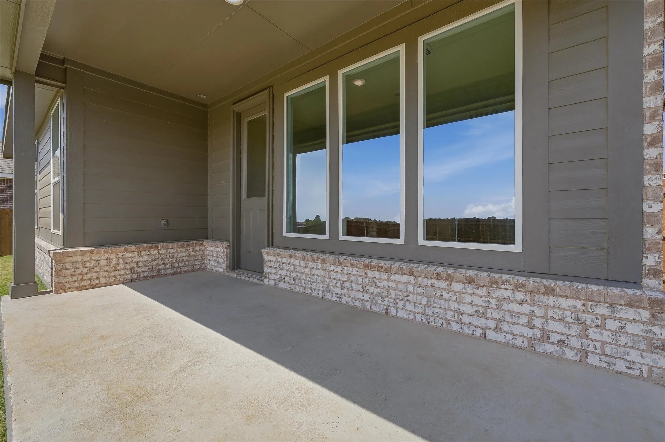 Covered concrete patio with a brick veneer foundation and siding exterior