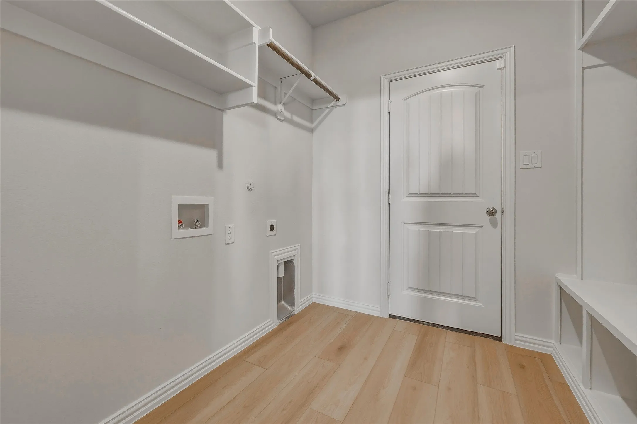 Built-in shelving, hanging rod, wood-finish flooring, paneled interior door, and built-in storage cubbies