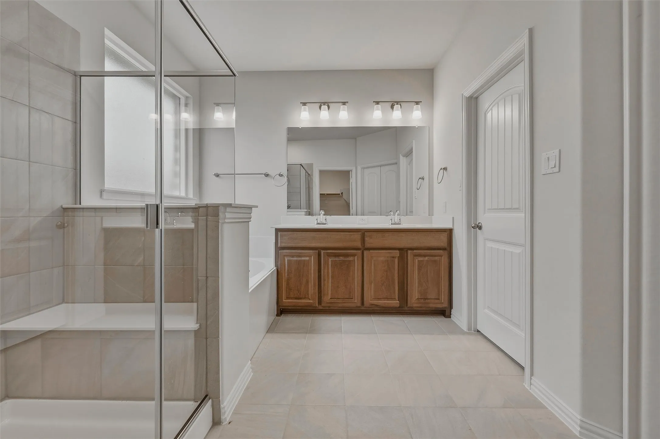 Expansive bathroom featuring a glass-enclosed shower, a double vanity with a wood-finish cabinet, and a built-in tub