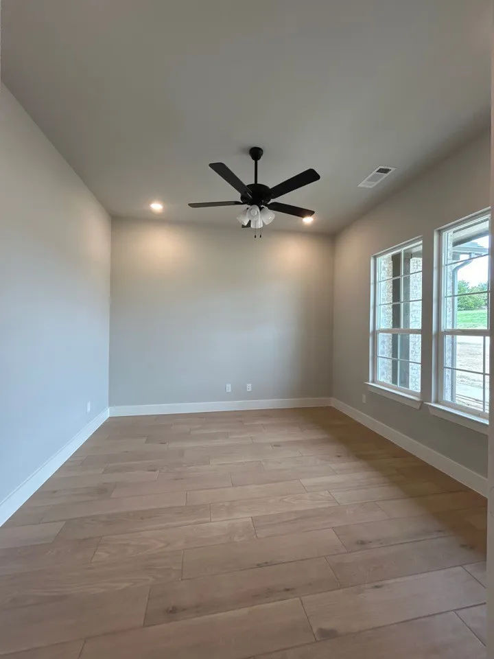 Wood-finish flooring, recessed lighting, ceiling fan with light kit, and multiple windows with white trim