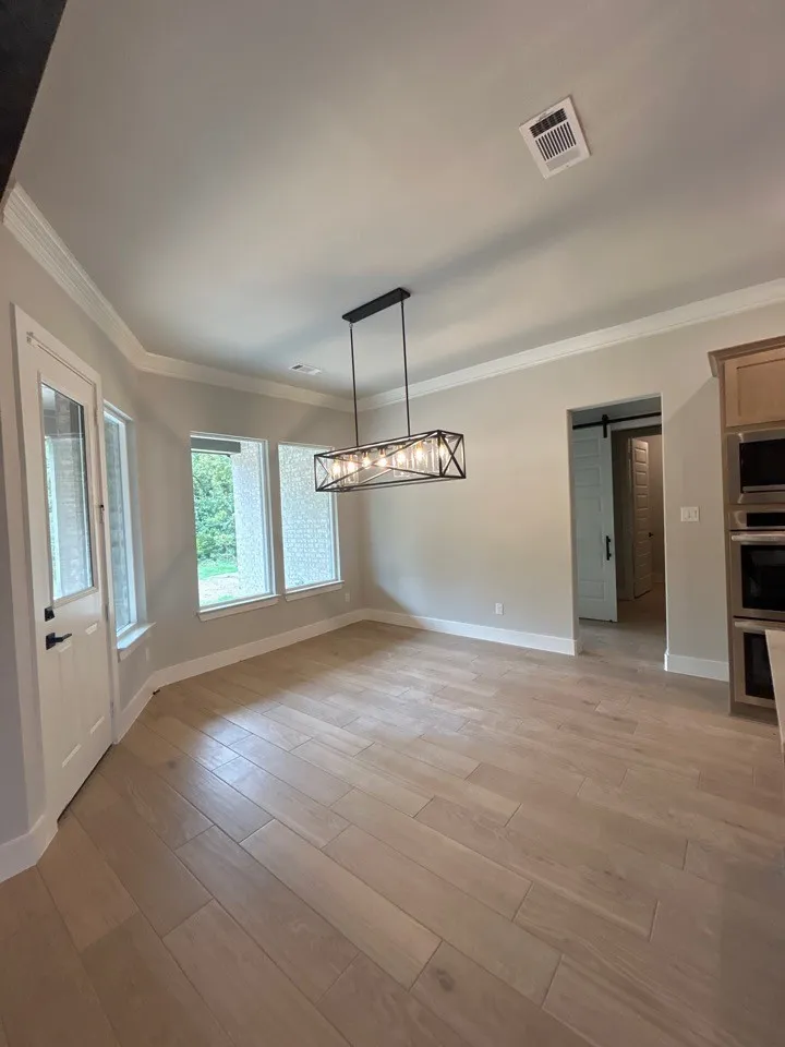 Wood-finish flooring throughout, featuring a linear multi-bulb chandelier