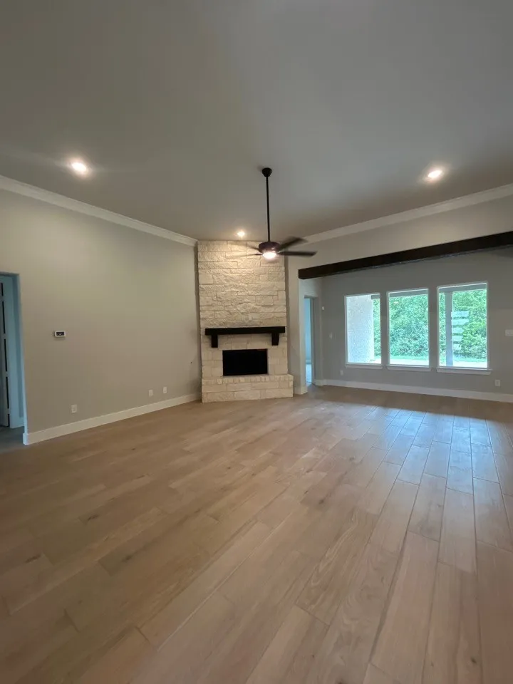 Open concept living area featuring light wood-finish flooring, a stone-clad fireplace with a dark mantel, a ceiling fan, and recessed lighting