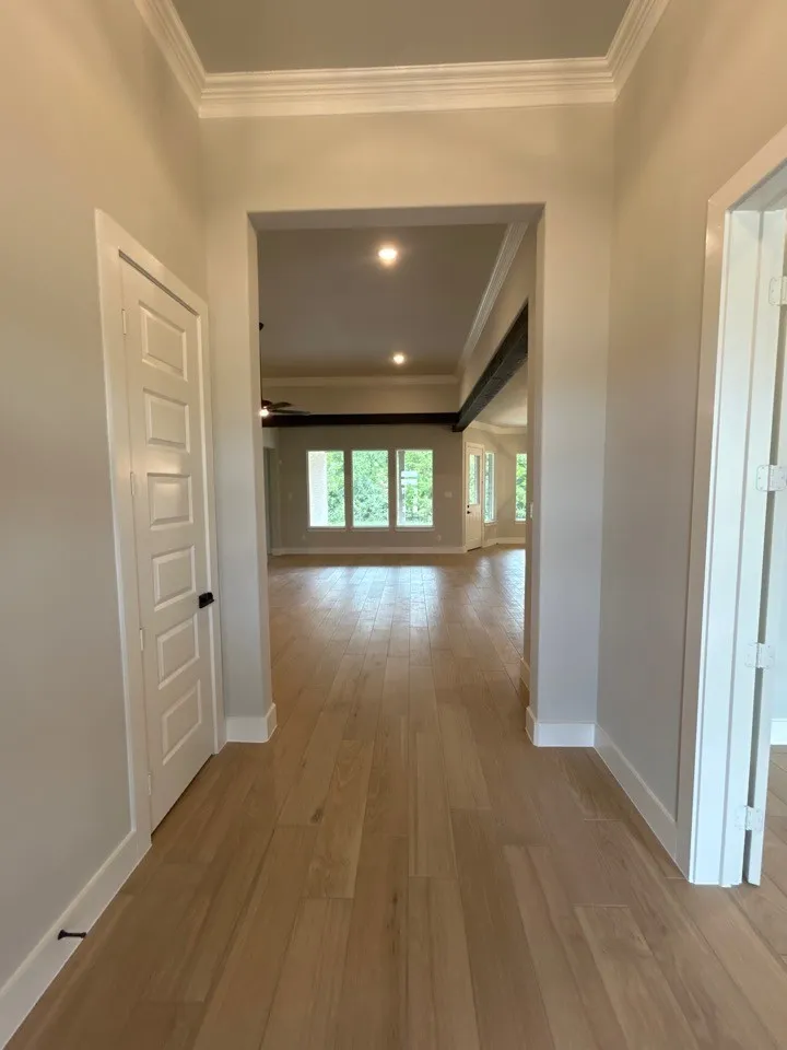 Crown molding, recessed lighting, wood-finish flooring, white trim, and a tray ceiling