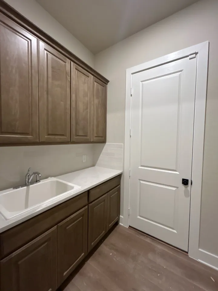 Wall-mounted cabinetry, integrated sink, wood-finish flooring, and white countertops