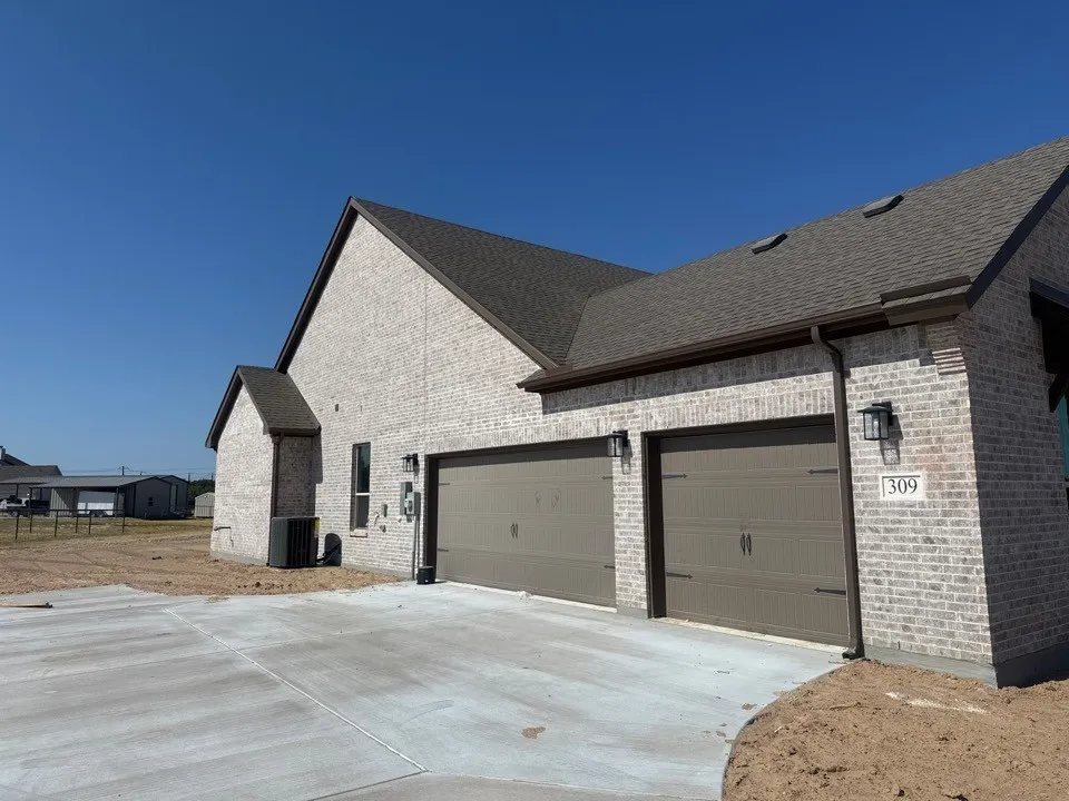 Brick exterior, two-car garage, concrete driveway, dark shingle roof, exterior wall lanterns