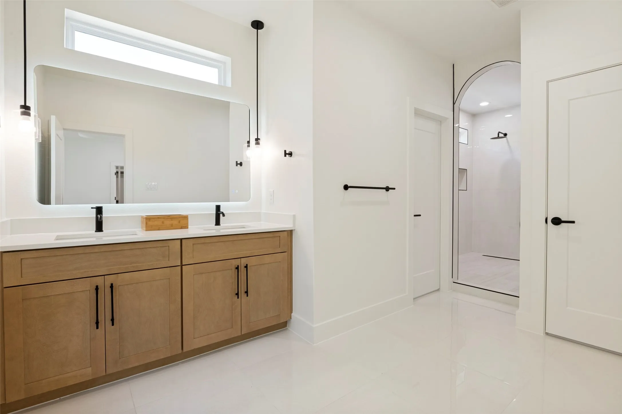 Dual vanity with wood-finish cabinetry, white countertops, and matte black fixtures