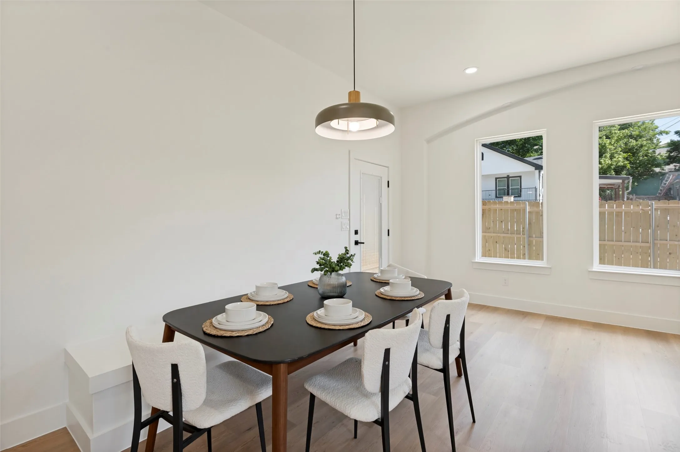 Dining area featuring light wood-finish flooring, recessed lighting, and a modern pendant light fixture