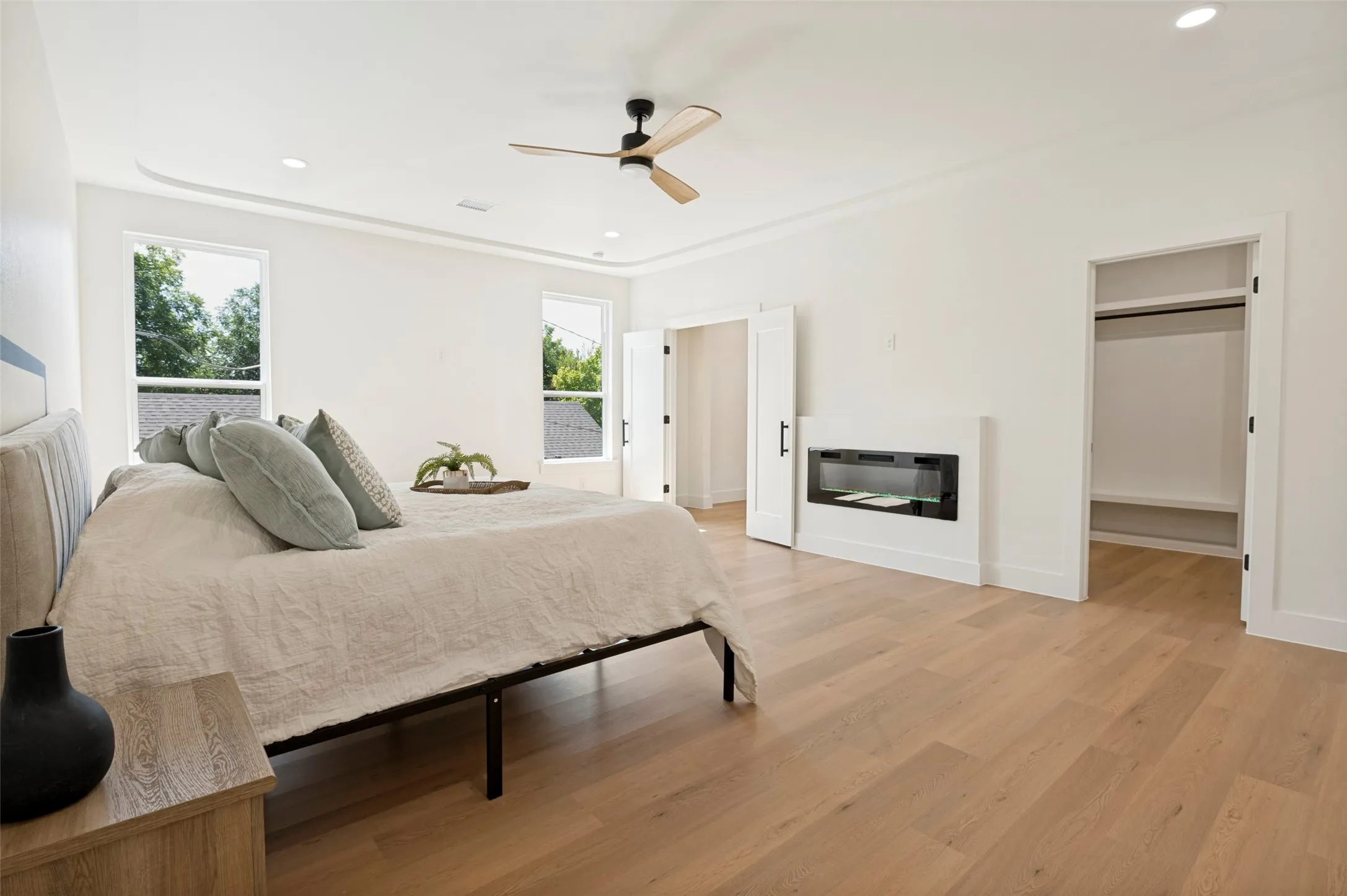 Spacious room featuring wood-finish flooring, a contemporary ceiling fan, and recessed lighting