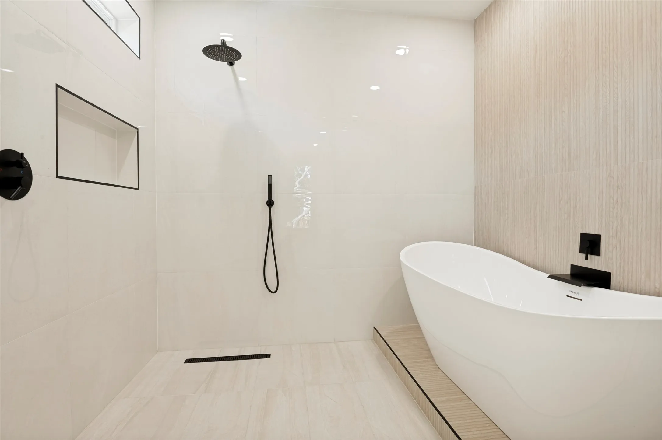 Freestanding soaking tub alongside a walk-in shower with a rain showerhead and handheld sprayer