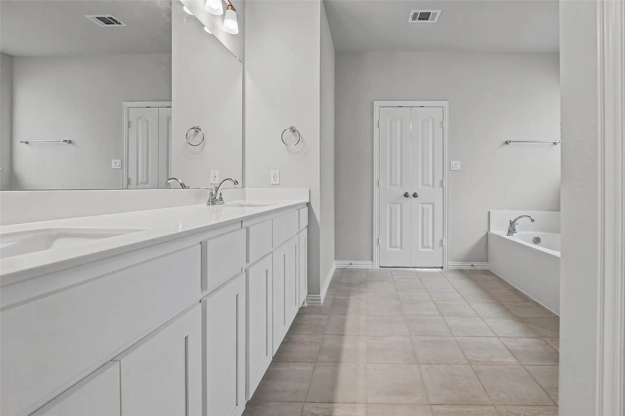 Dual vanity with integrated sinks, white cabinetry, and a large mirror