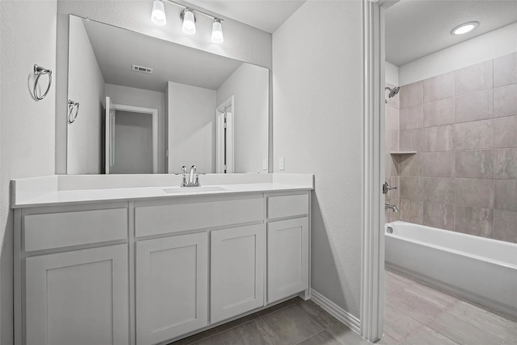 Vanity with integrated sink and chrome faucet, large rectangular mirror, and overhead track lighting