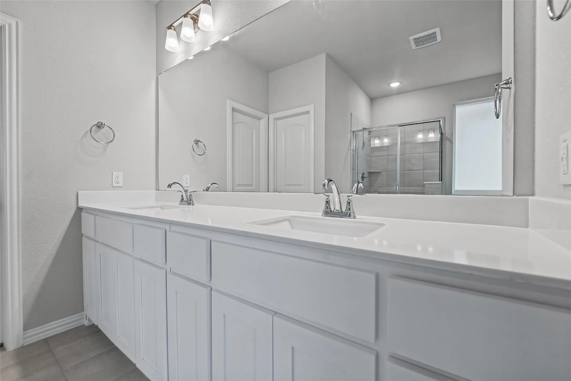 Dual vanity with integrated sinks, chrome fixtures, and a large wall-mounted mirror
