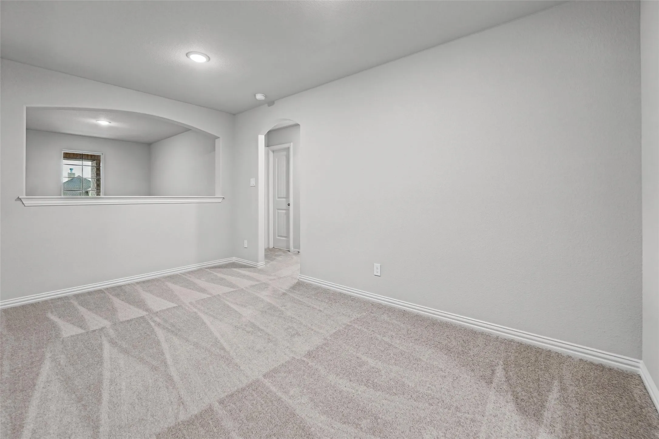 Recessed lighting, arched doorway, arched interior opening, neutral wall tones, and patterned carpeting