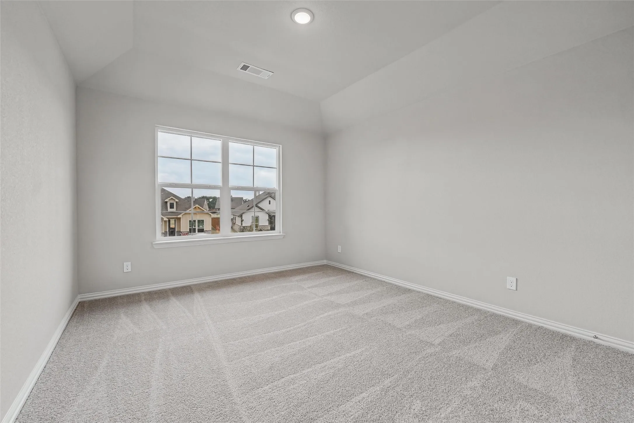 Recessed lighting, vaulted ceiling, neutral wall color, light-toned carpeting, and a multi-pane window