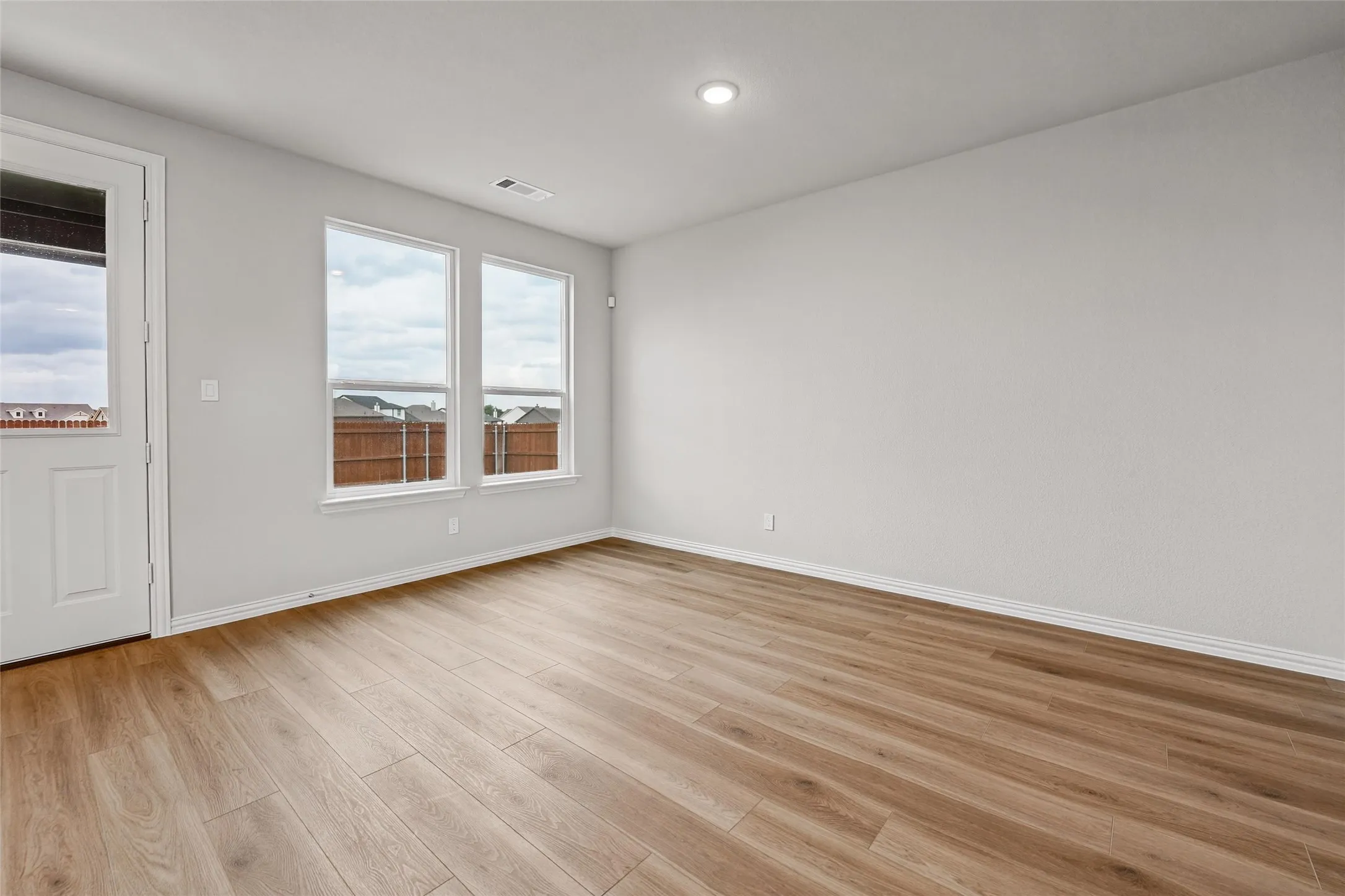 Wood-finish flooring, recessed lighting, and multiple windows with white trim