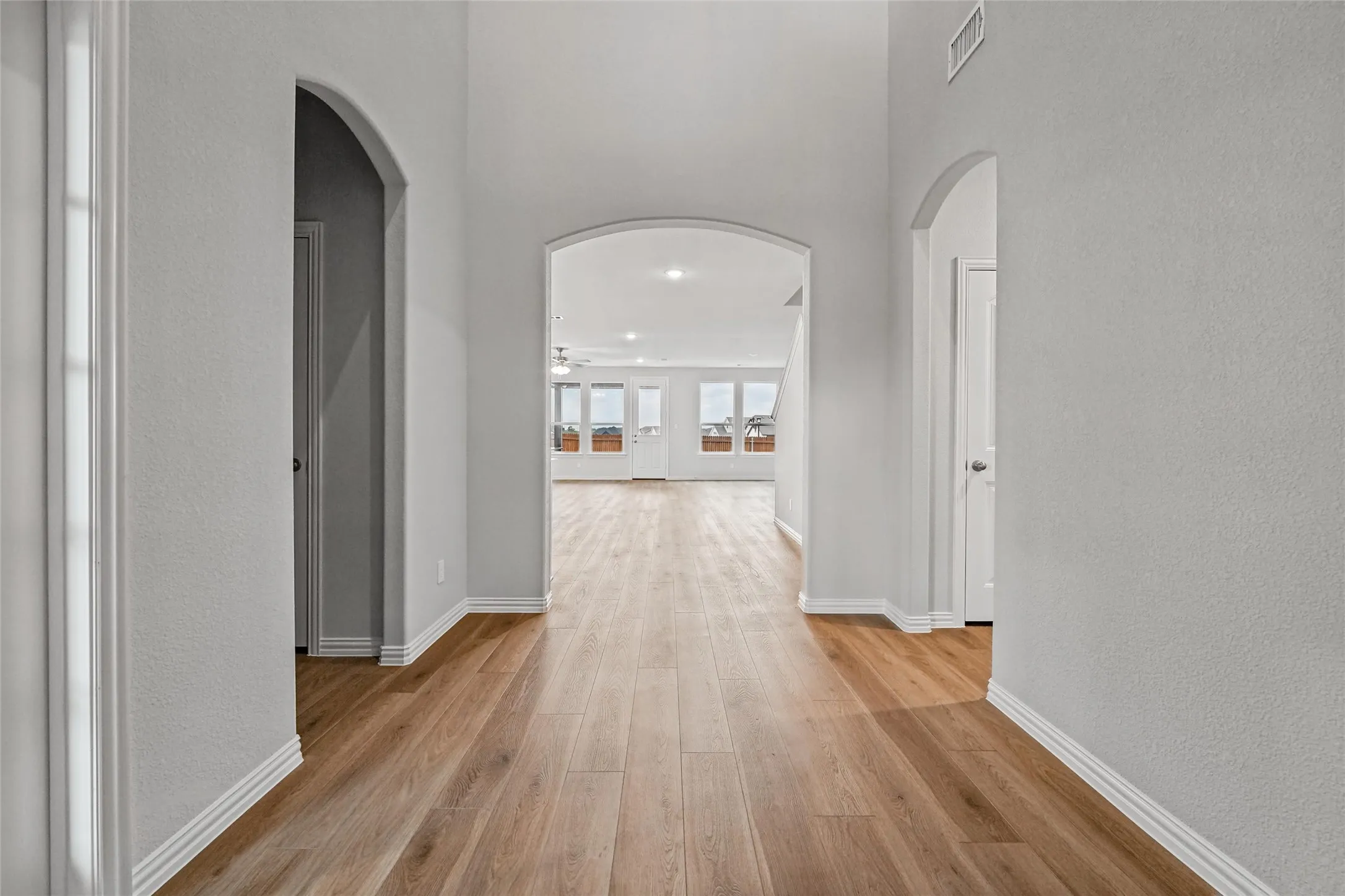 Archway entries, wood-finish flooring, white trim, and light gray wall finishes