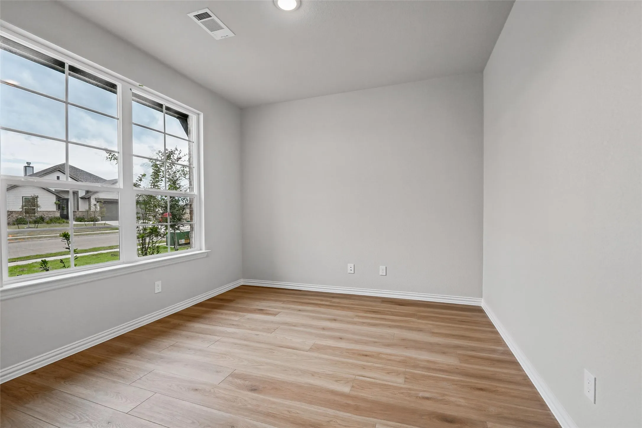 Expansive windows with grid patterns, wood-finish flooring, recessed lighting, and neutral wall tones