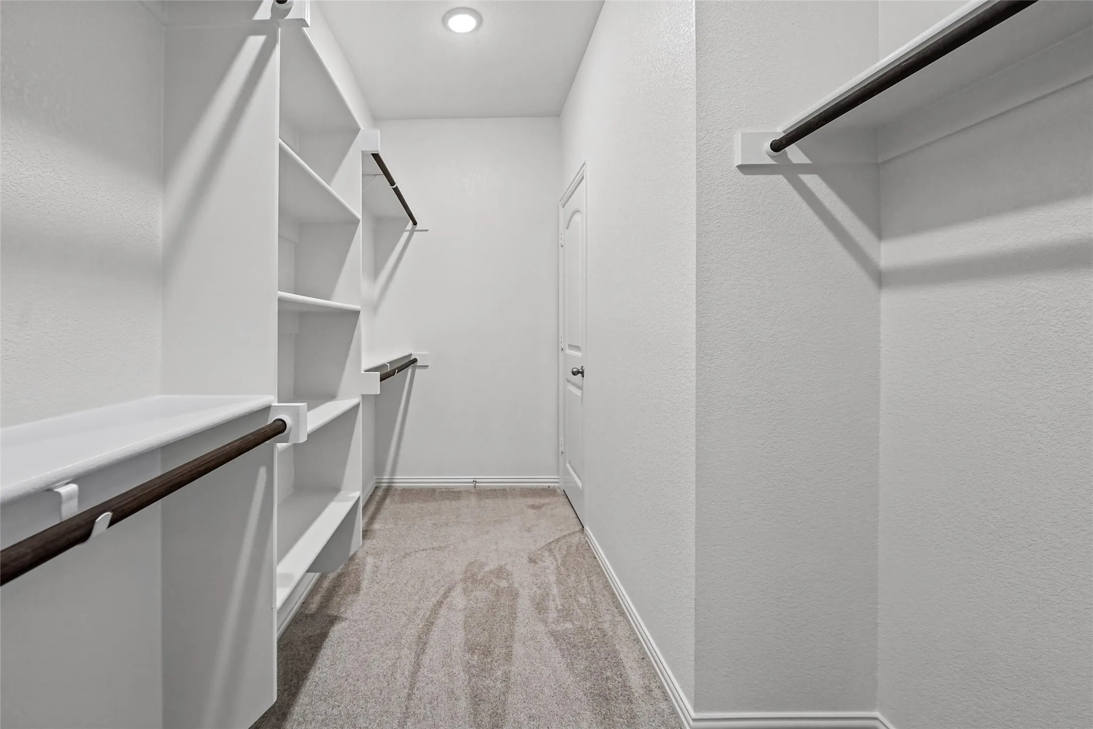 Walk-in closet featuring built-in shelving, multiple hanging rods, recessed lighting, and carpet flooring