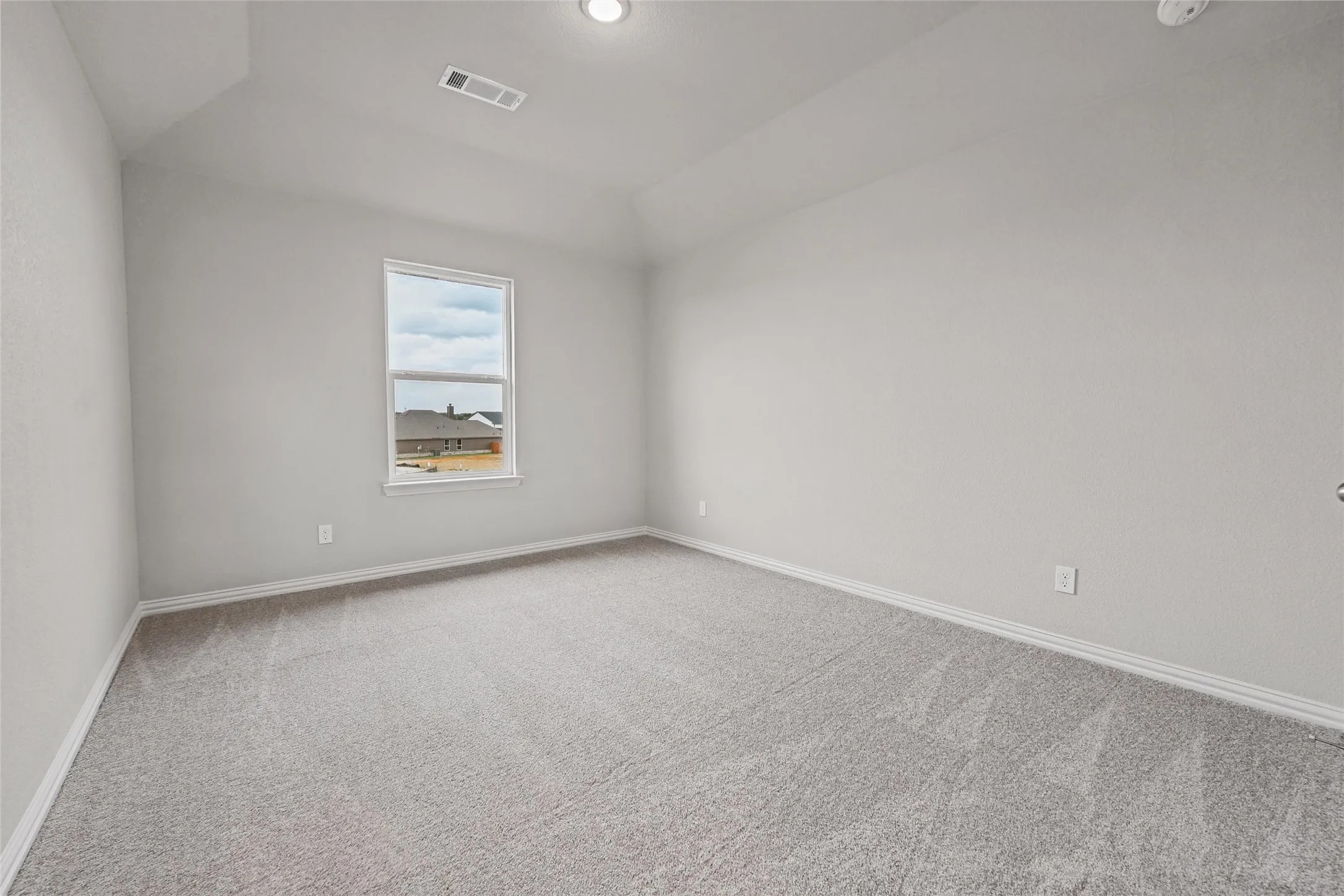 Neutral-toned carpeting, light gray wall paint, and a single window with white trim