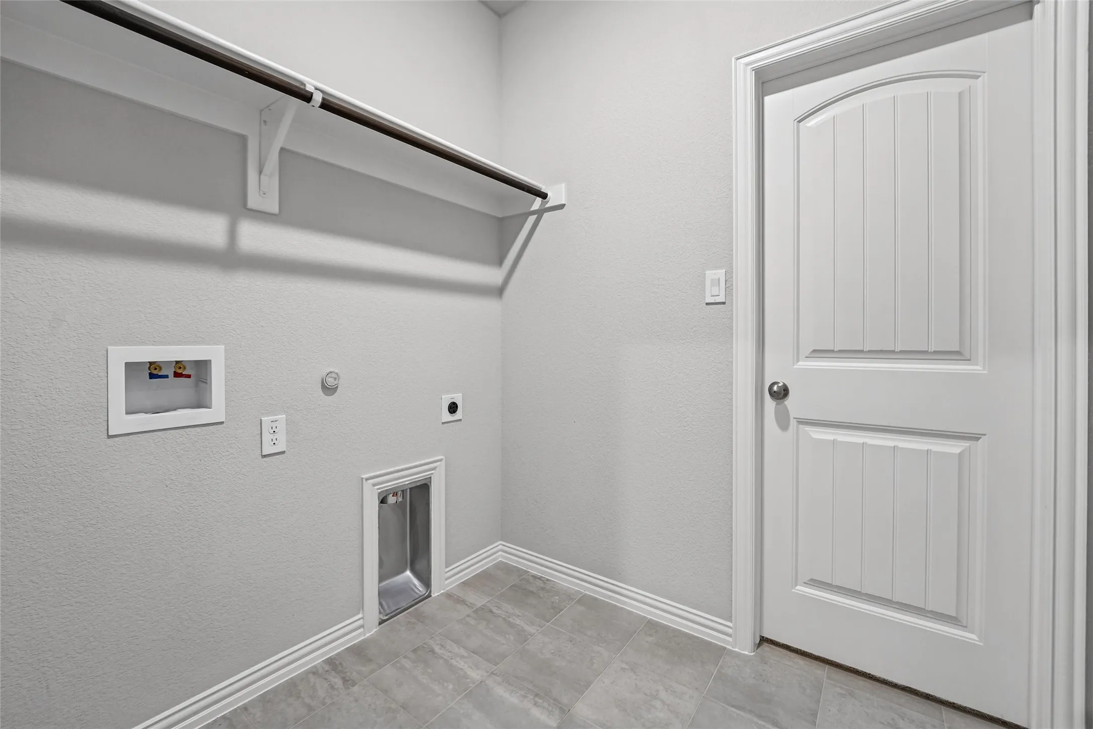 Utility space featuring a laundry hookup, overhead storage shelf, and tile flooring