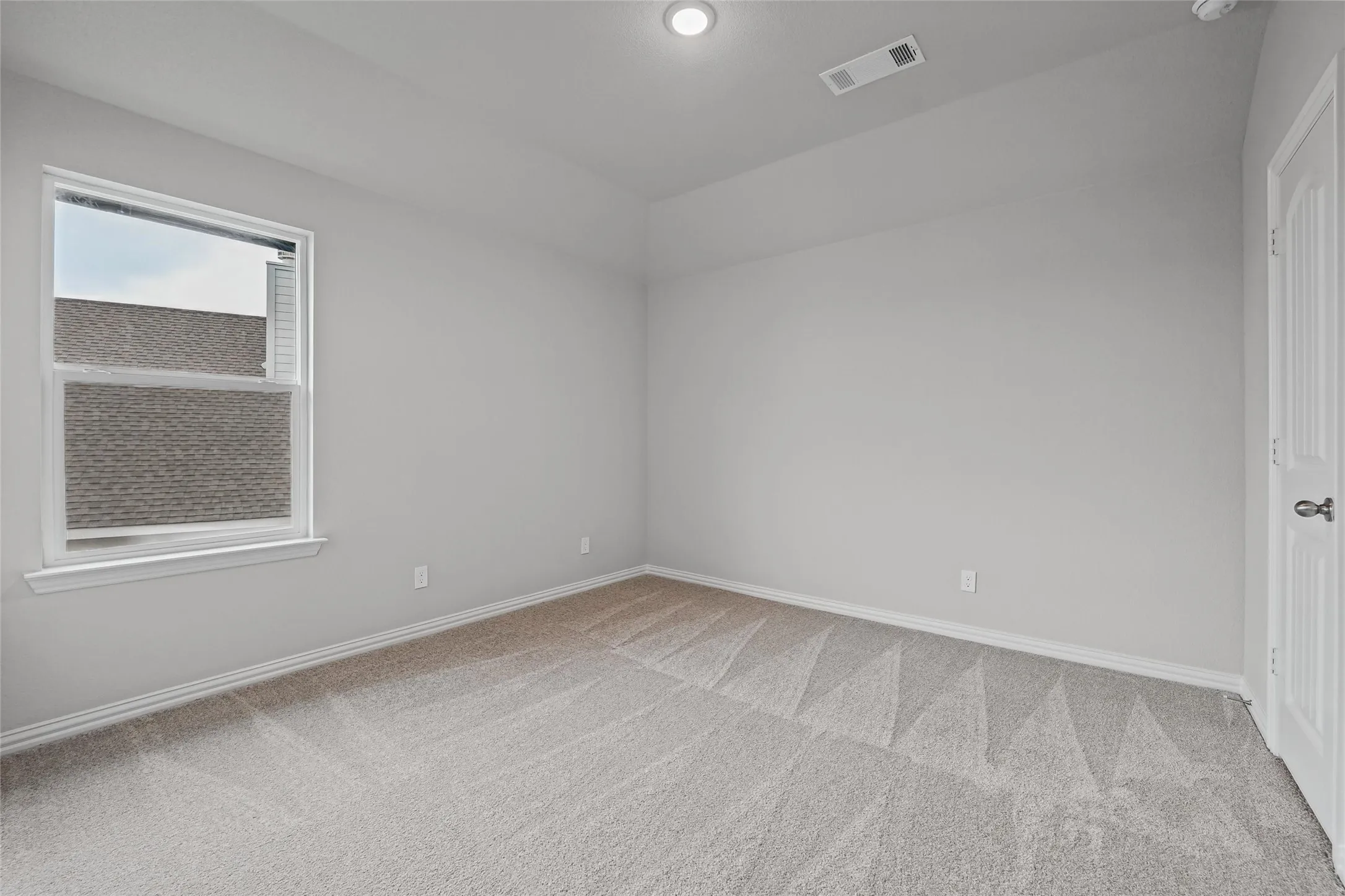 Wall-to-wall carpeting, recessed lighting, and a single window with white trim