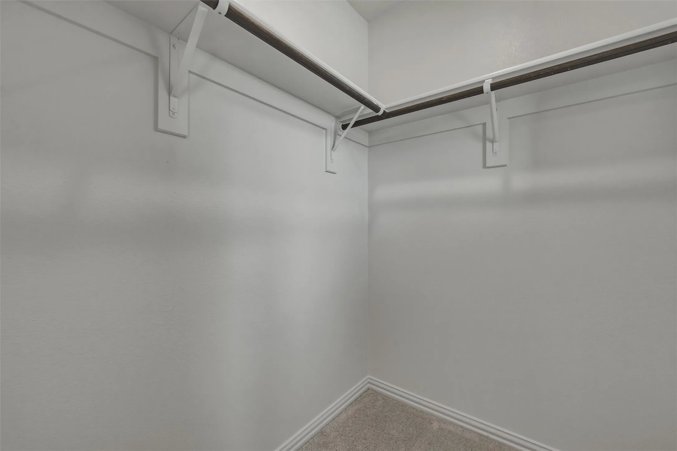 Wall-to-wall carpeting with corner shelving and hanging rods