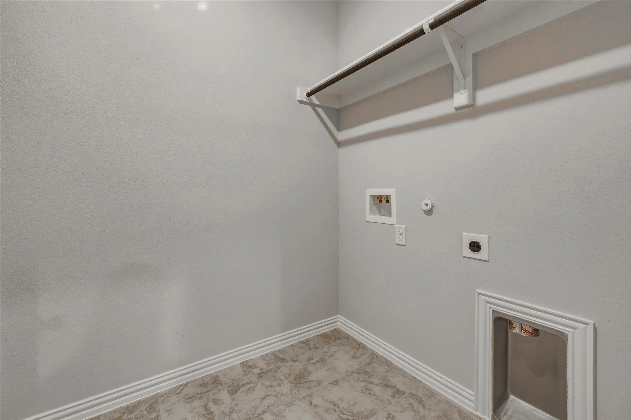Laundry area featuring neutral wall paint, a clothes hanging rod, tiled flooring, and appliance hookups