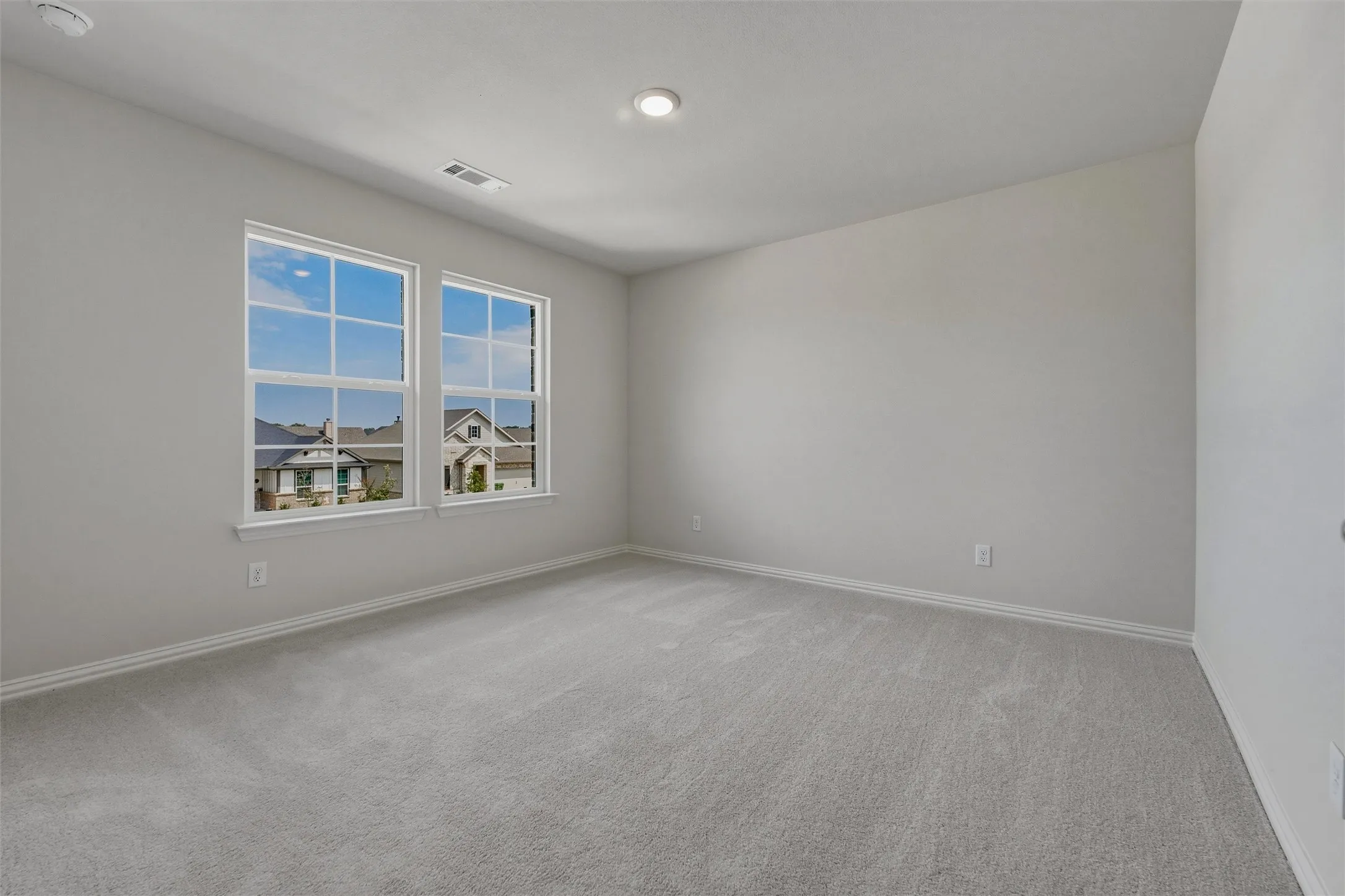 Recessed ceiling lighting, light gray wall paint, and gray carpeted flooring
