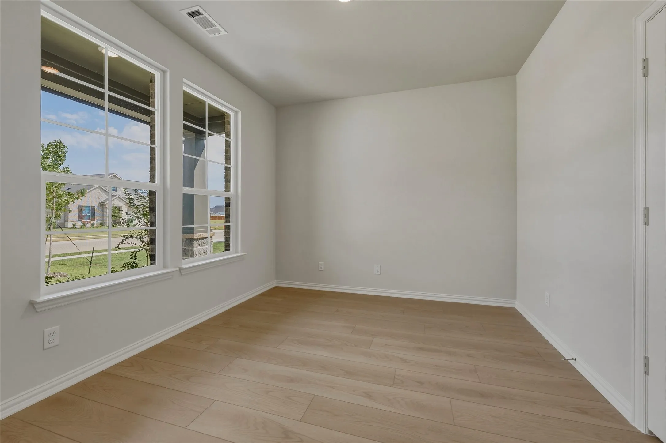 Neutral tone wall paint, wood-finish flooring, and multiple double-hung windows