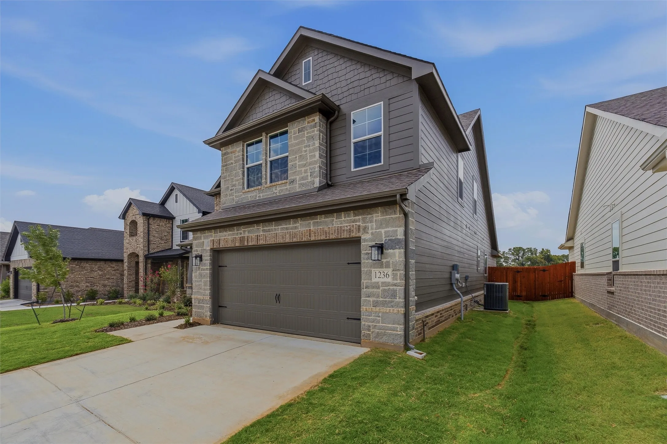 Stone and siding exterior with a dark gray overhead garage door