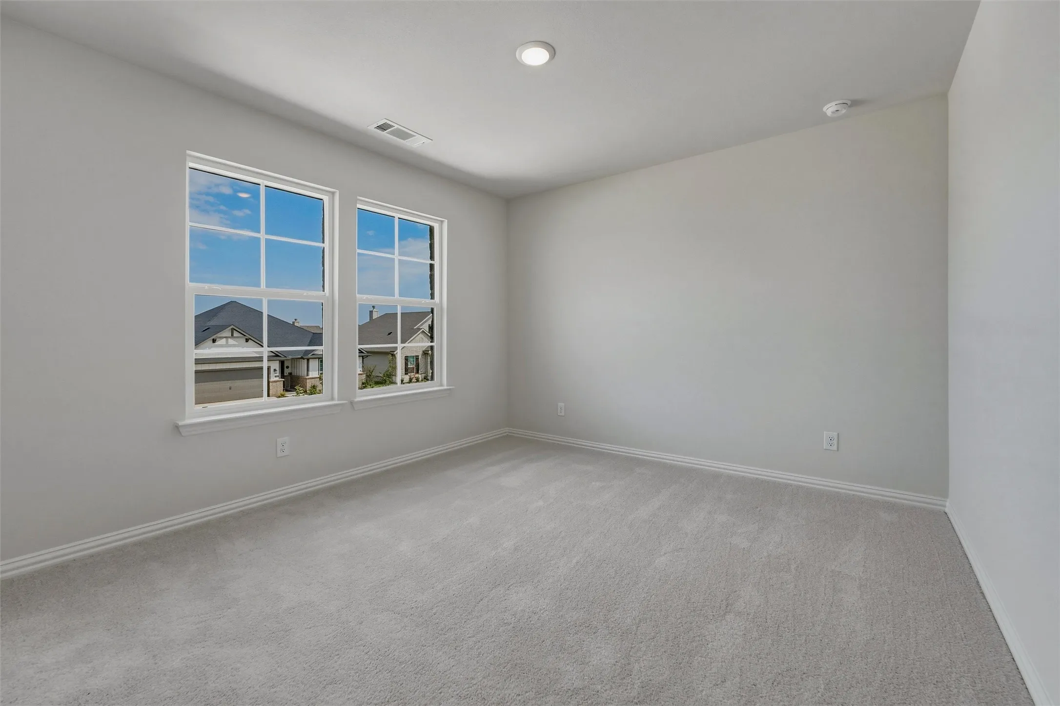 Light gray wall finishes, recessed ceiling lighting, light gray carpeting, and two double-hung windows