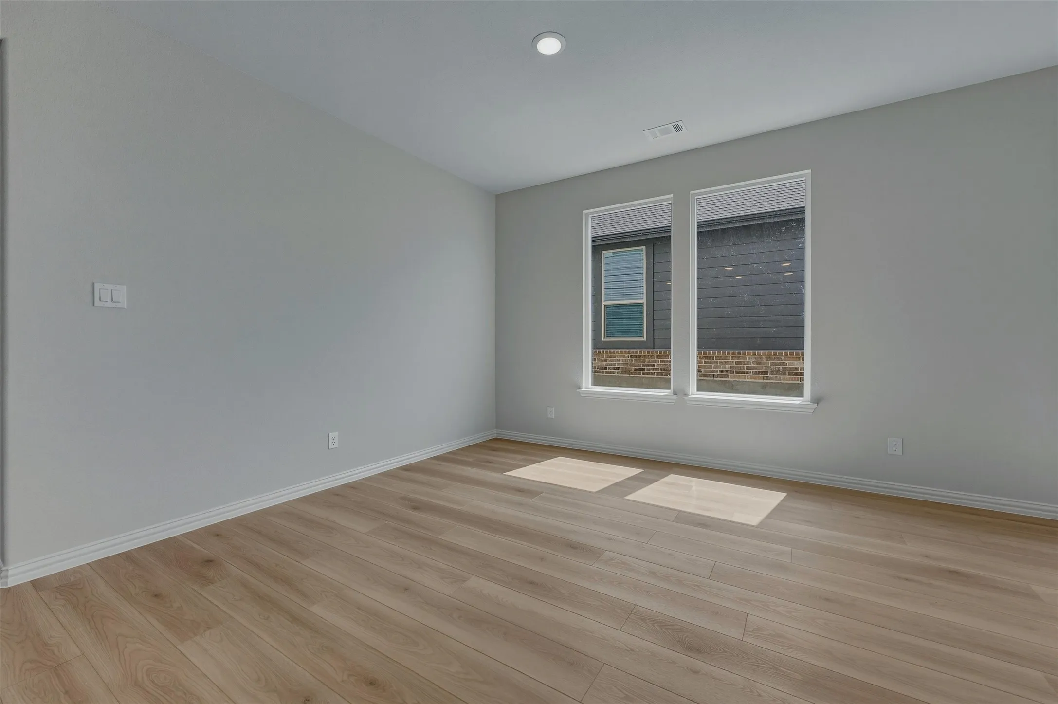 Wood-finish flooring, recessed lighting, and dual windows with white trim